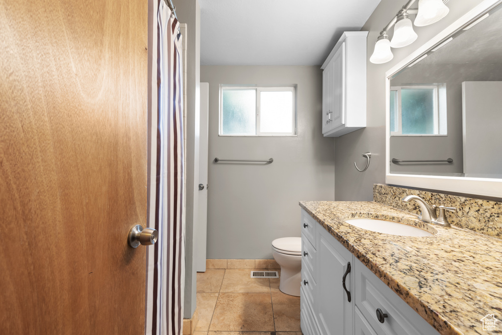 Bathroom with toilet, healthy amount of natural light, vanity, and baseboards