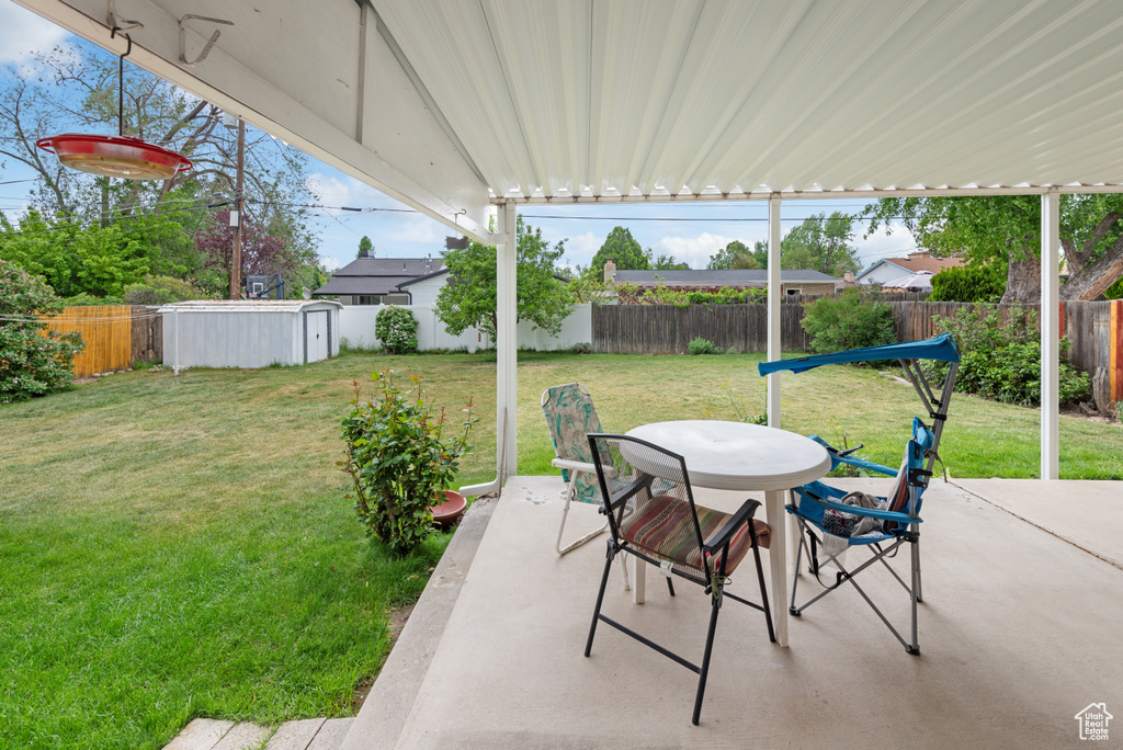 View of patio / terrace featuring outdoor dining area, a storage shed, and an outbuilding