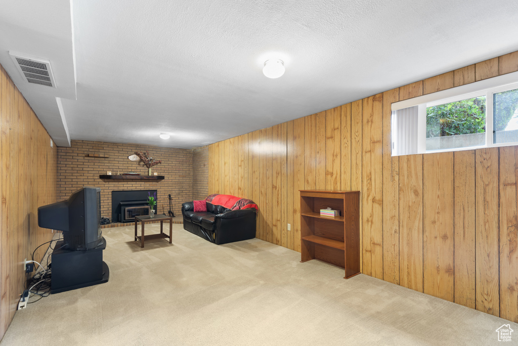 Sitting room with carpet flooring, wood walls, a fireplace, and a textured ceiling