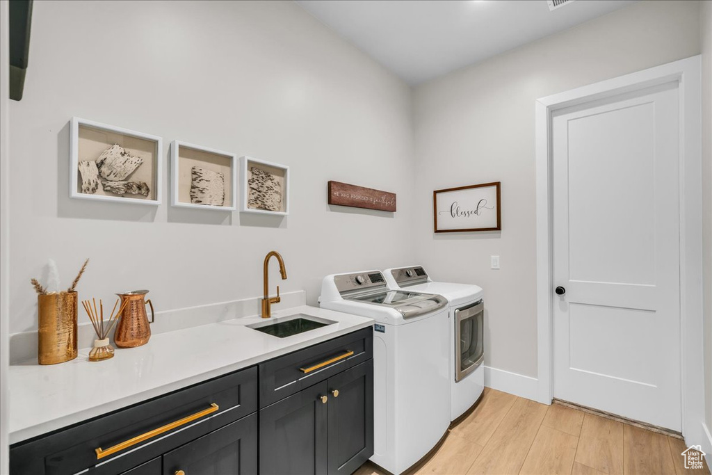 Laundry room with cabinet space, washing machine and clothes dryer, light wood-type flooring, and baseboards