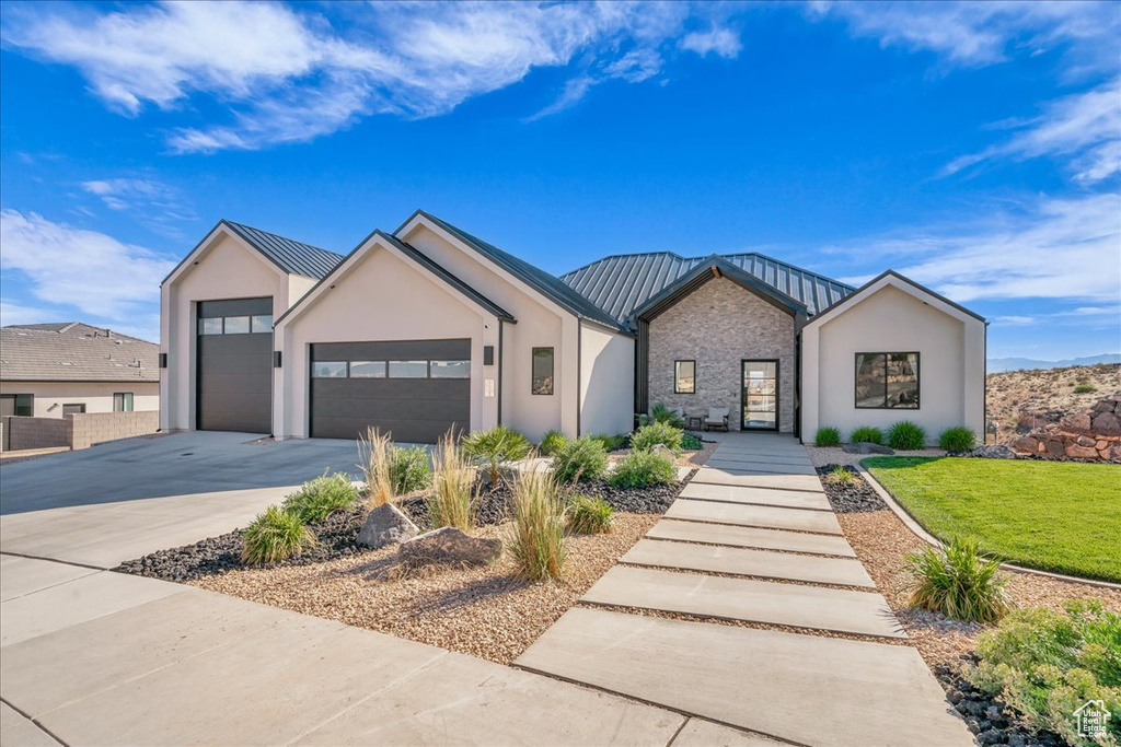 View of front of home featuring concrete driveway, an attached garage, a standing seam roof, stucco siding, and metal roof