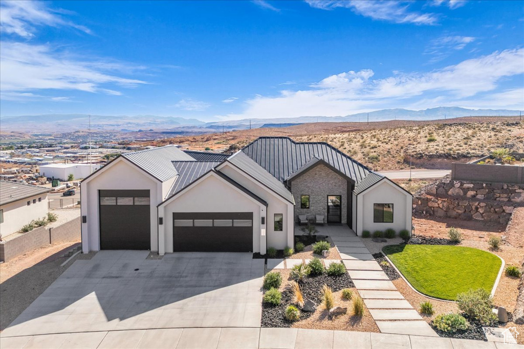 Modern inspired farmhouse with a garage, a mountain view, concrete driveway, and stucco siding