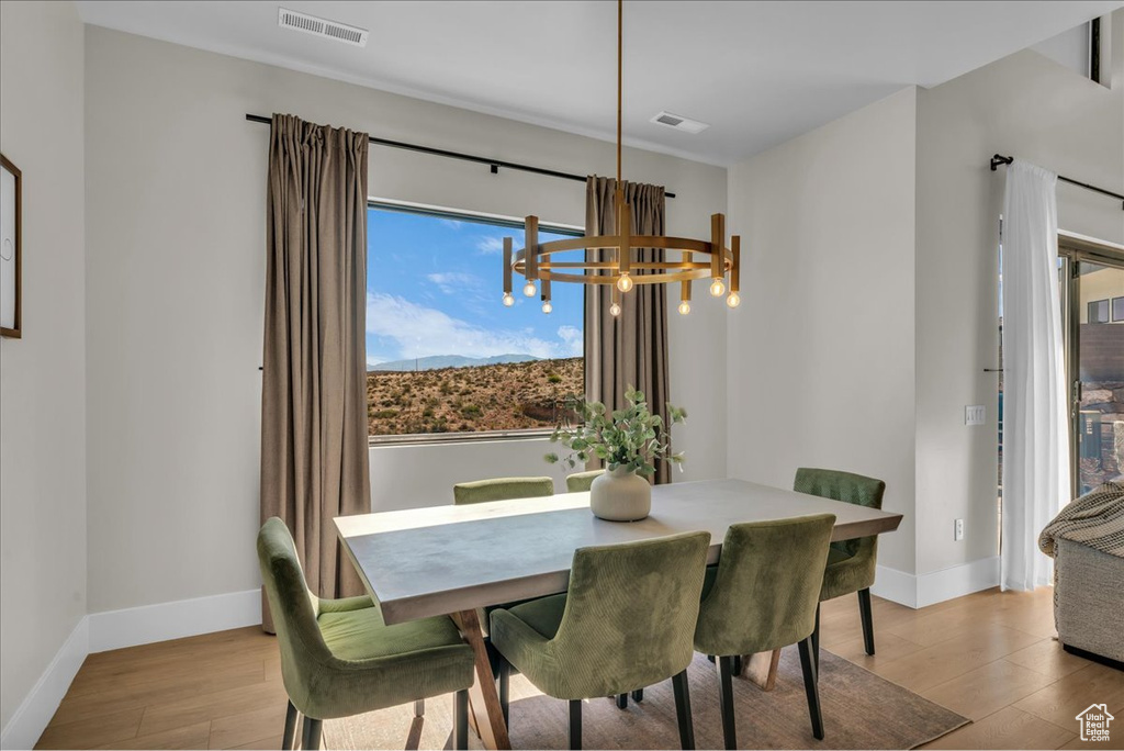 Dining room with a chandelier, wood finished floors, and baseboards