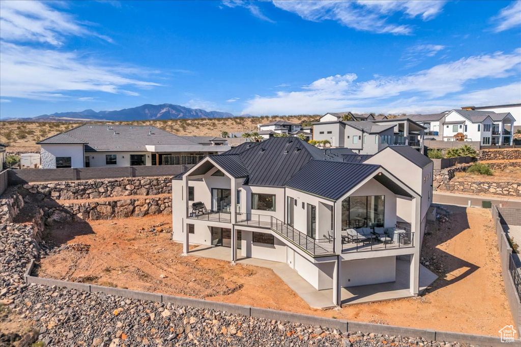 Rear view of property featuring a patio area, a residential view, a standing seam roof, and stucco siding