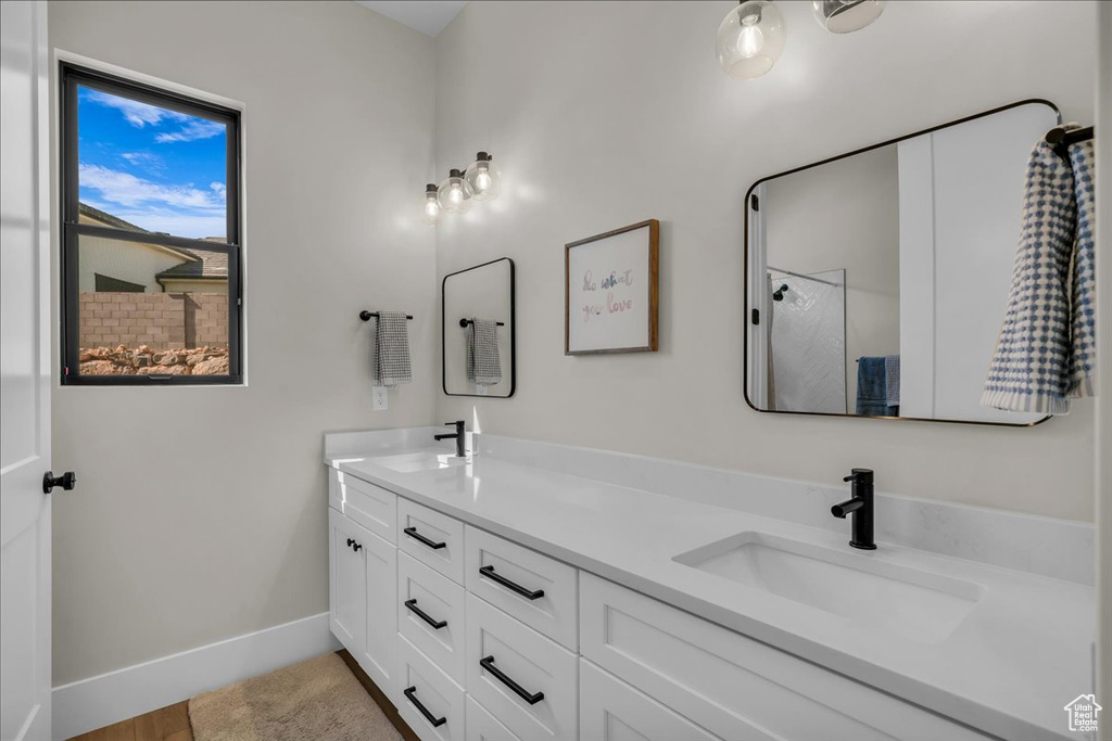 Bathroom featuring double vanity, baseboards, and a shower