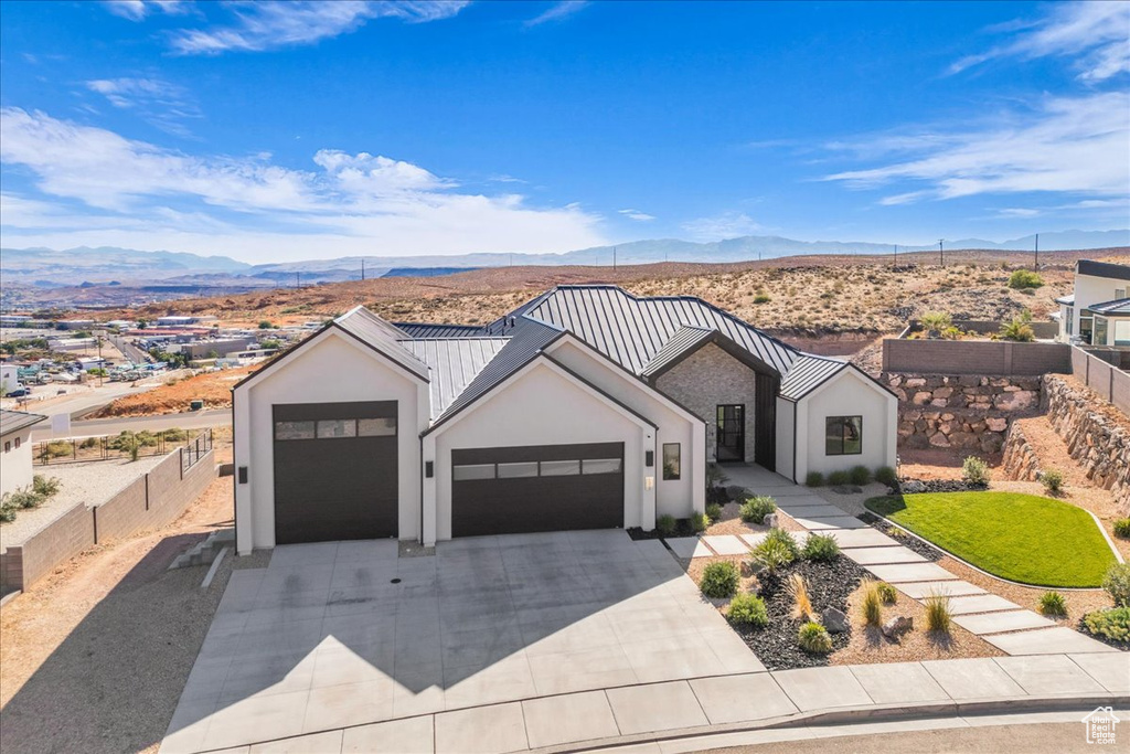 Modern inspired farmhouse with a mountain view, stucco siding, concrete driveway, a garage, and fence
