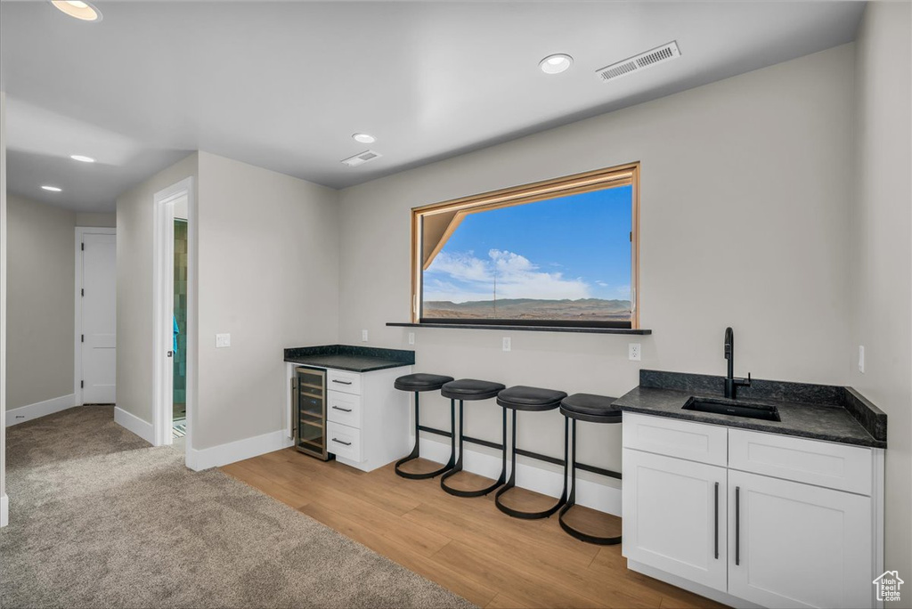 Indoor dry bar with beverage cooler, baseboards, recessed lighting, and light wood-type flooring