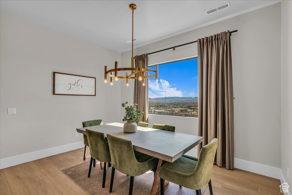Dining room with a chandelier, baseboards, and light wood-style flooring