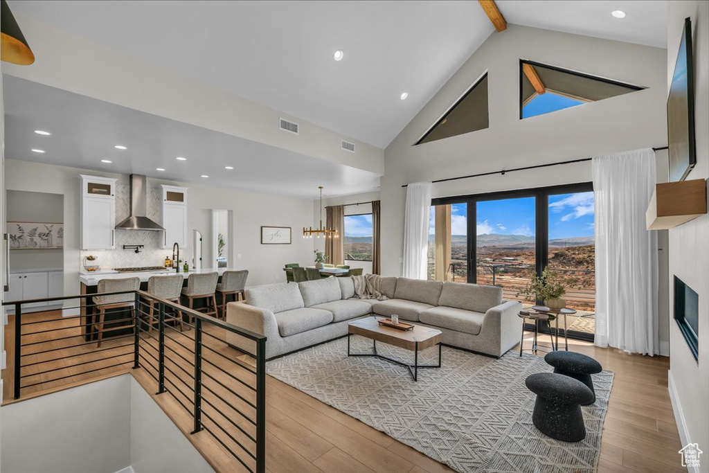 Living room with wood finished floors, high vaulted ceiling, beamed ceiling, recessed lighting, and a chandelier