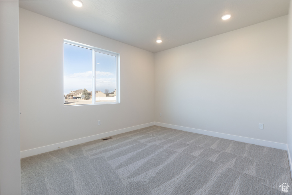 Spare room with light colored carpet, baseboards, and recessed lighting