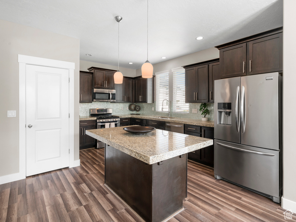 Kitchen featuring appliances with stainless steel finishes, dark brown cabinetry, decorative backsplash, dark wood-style flooring, and recessed lighting