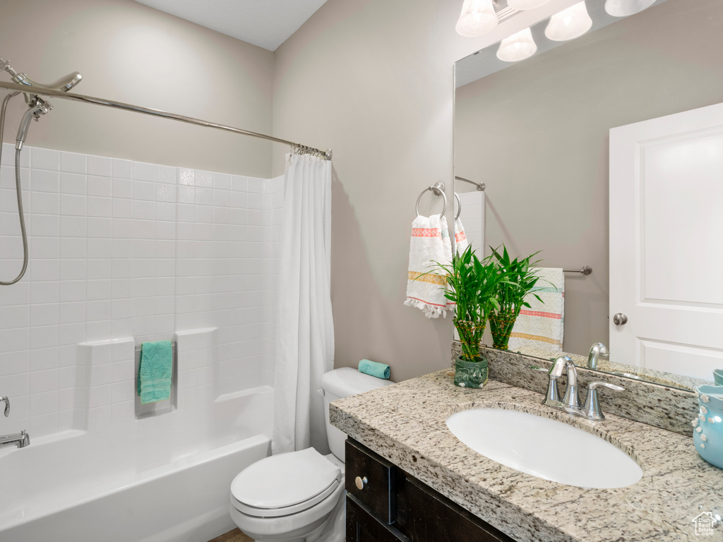 Bathroom featuring shower / bathtub combination with curtain, toilet, and vanity
