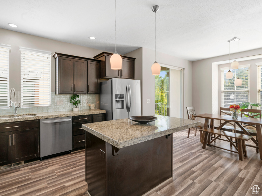 Kitchen featuring appliances with stainless steel finishes, a sink, dark brown cabinets, light wood-style flooring, and recessed lighting