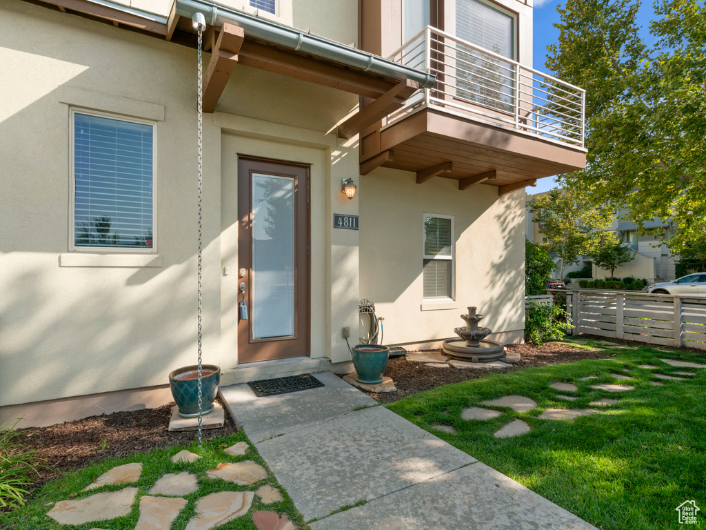 Entrance to property featuring a balcony, fence, and stucco siding
