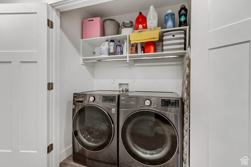 Laundry room with separate washer and dryer, wood finished floors, and baseboards