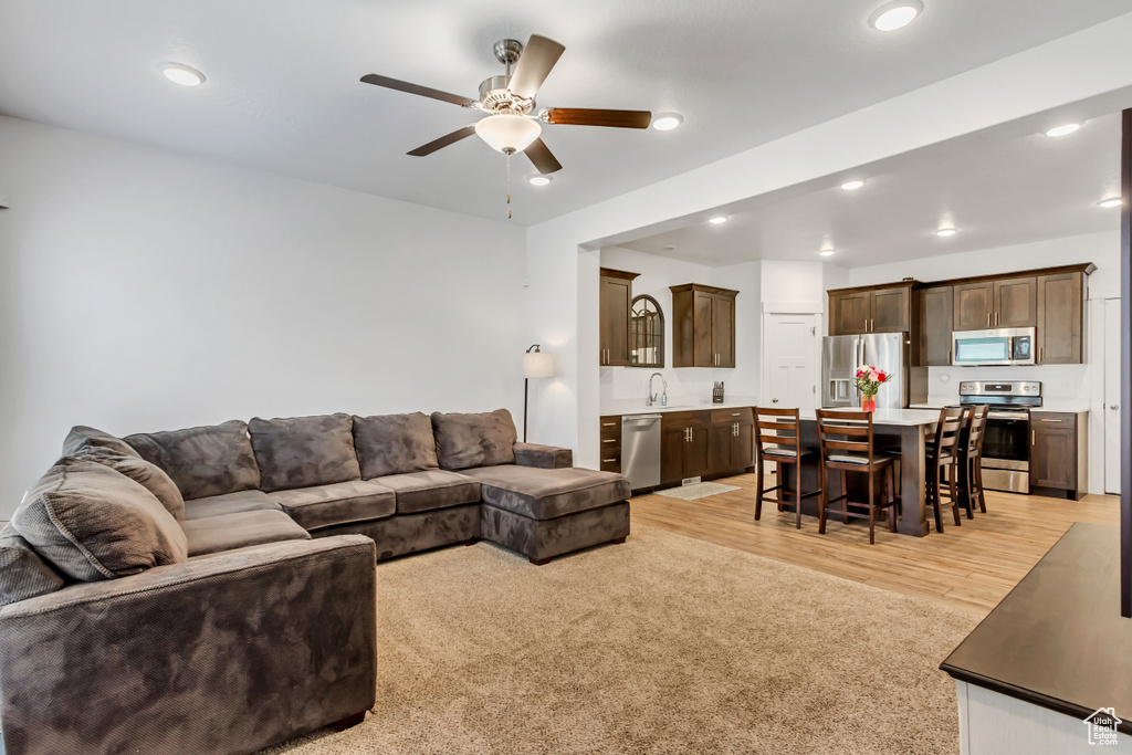 Living area with a ceiling fan, light wood-style floors, and recessed lighting