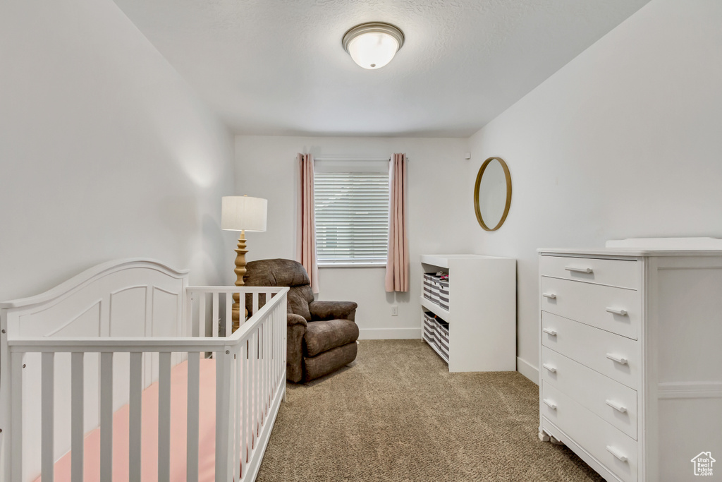 Bedroom featuring light colored carpet and a crib