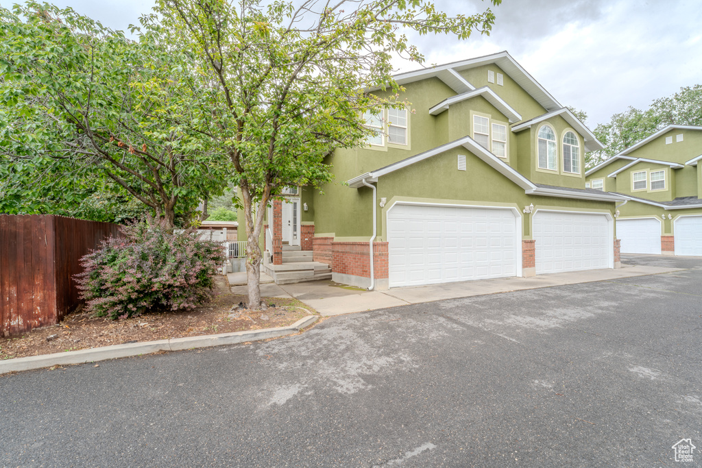 View of front of home featuring fence, a garage, stucco siding, and asphalt driveway