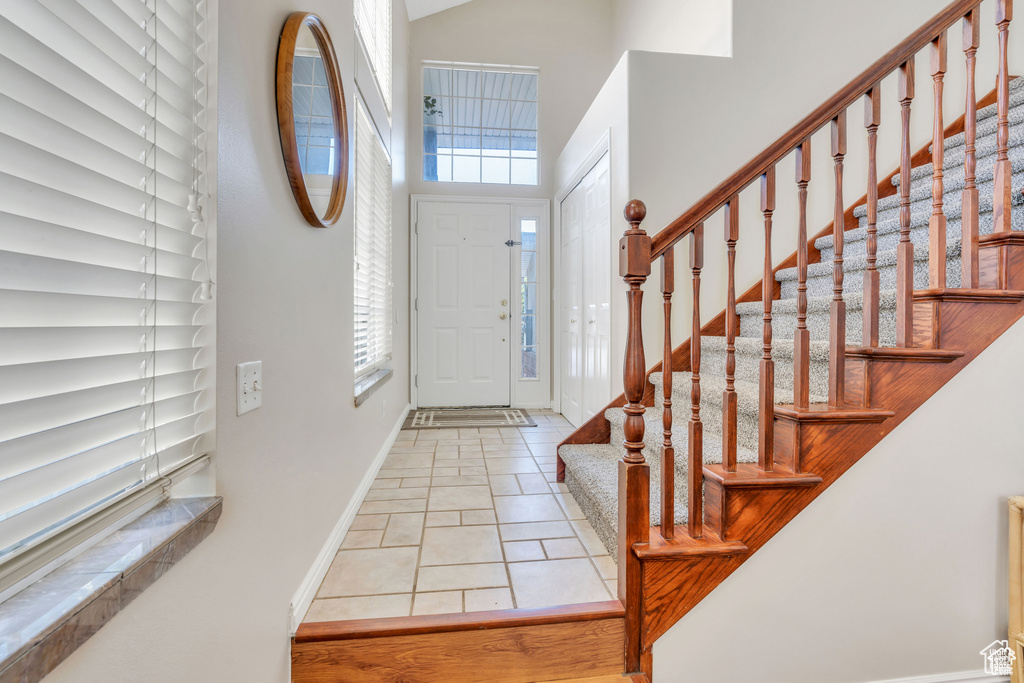 Tiled entryway with baseboards and a high ceiling