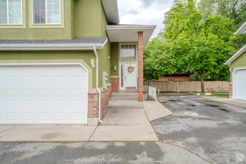 Doorway to property with stucco siding, fence, driveway, and brick siding