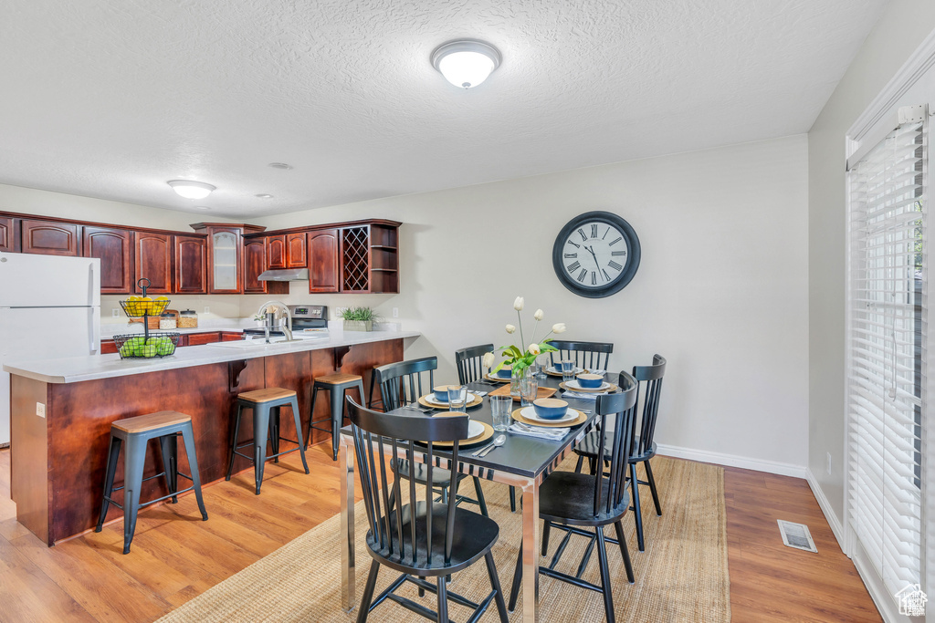 Dining room with light wood-style floors, baseboards, and a textured ceiling
