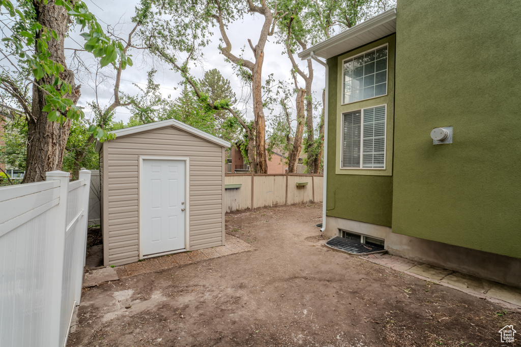 View of patio featuring a storage shed, a fenced backyard, and an outbuilding