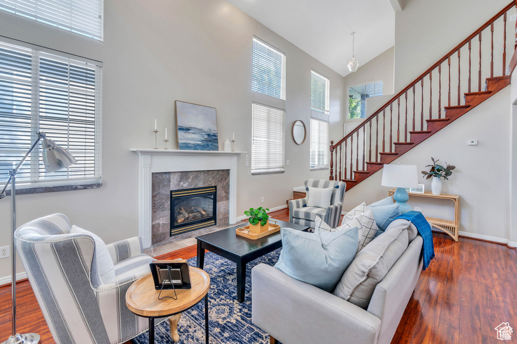 Living area featuring high vaulted ceiling, wood finished floors, stairway, a high end fireplace, and baseboards