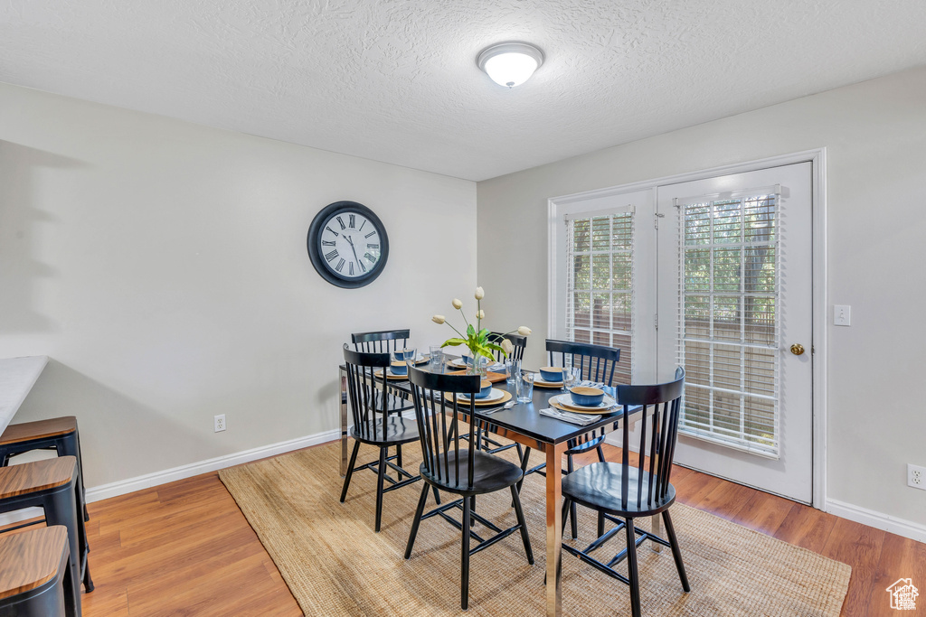 Dining area featuring a textured ceiling, wood finished floors, and baseboards