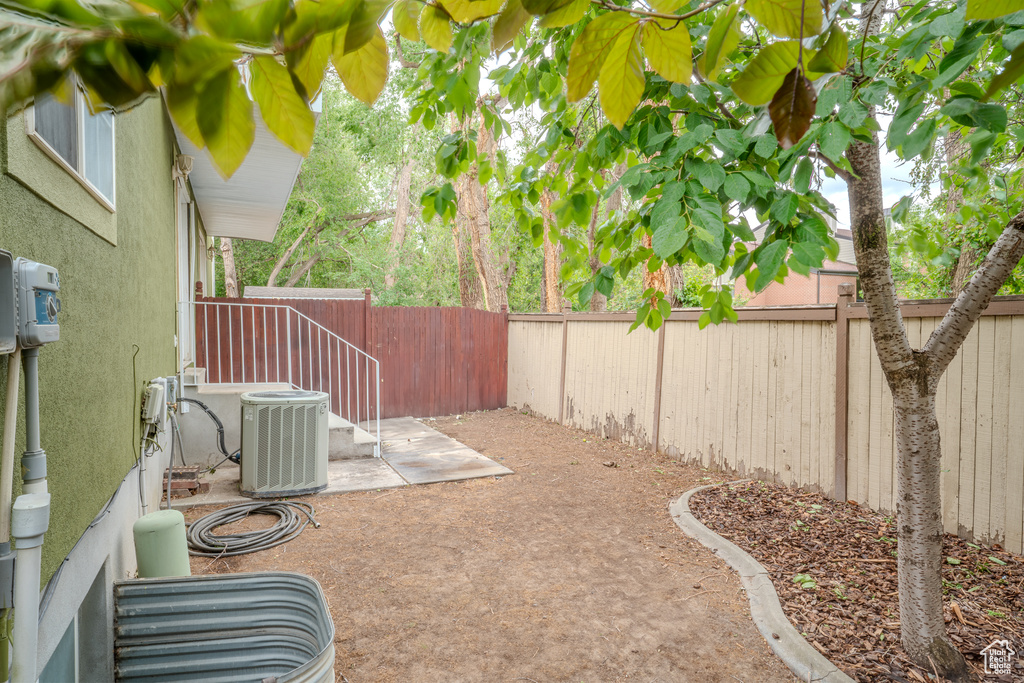 Fenced backyard with cooling unit and a patio area
