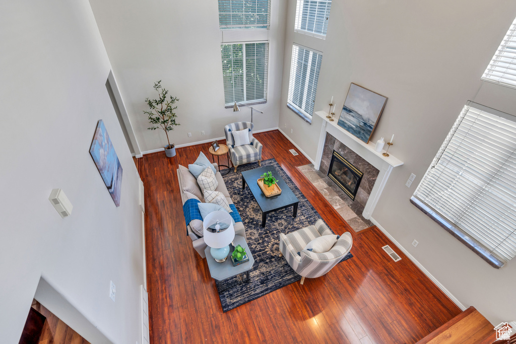 Living area featuring a high ceiling, wood finished floors, a premium fireplace, and baseboards