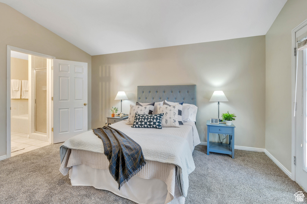 Carpeted bedroom with lofted ceiling, baseboards, and connected bathroom