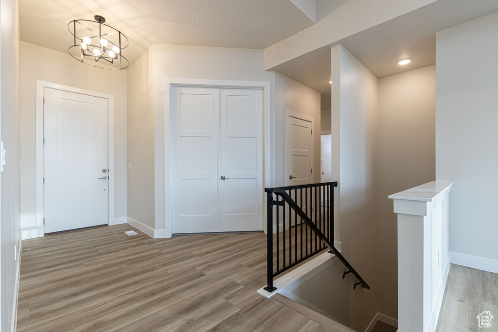 Corridor with an upstairs landing, light wood-style flooring, baseboards, and a chandelier
