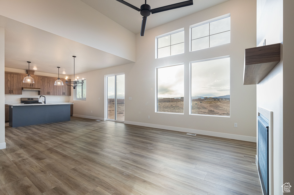 Unfurnished living room with ceiling fan, baseboards, a fireplace, wood finished floors, and a sink