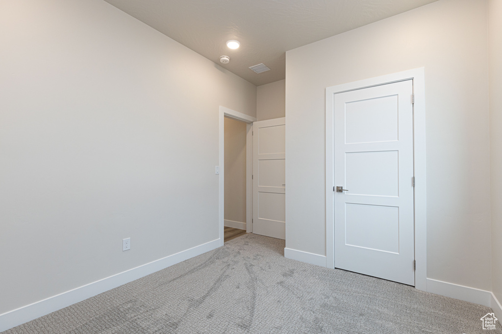 Unfurnished bedroom featuring light colored carpet and baseboards