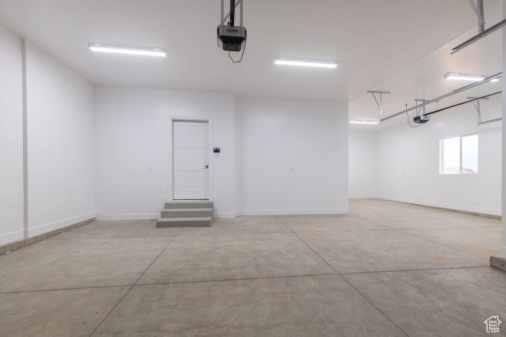 Garage featuring a garage door opener and baseboards