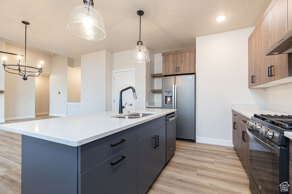 Kitchen featuring a sink, appliances with stainless steel finishes, light wood-type flooring, light countertops, and baseboards