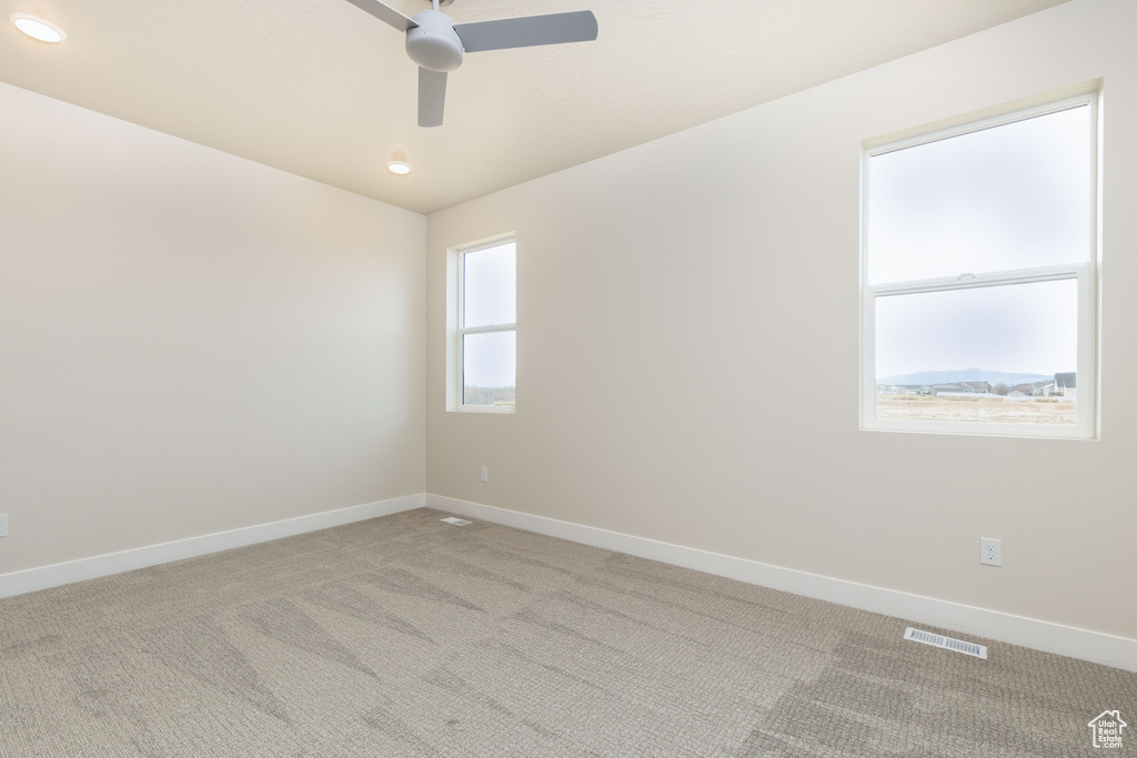 Unfurnished room with a ceiling fan, light carpet, and baseboards