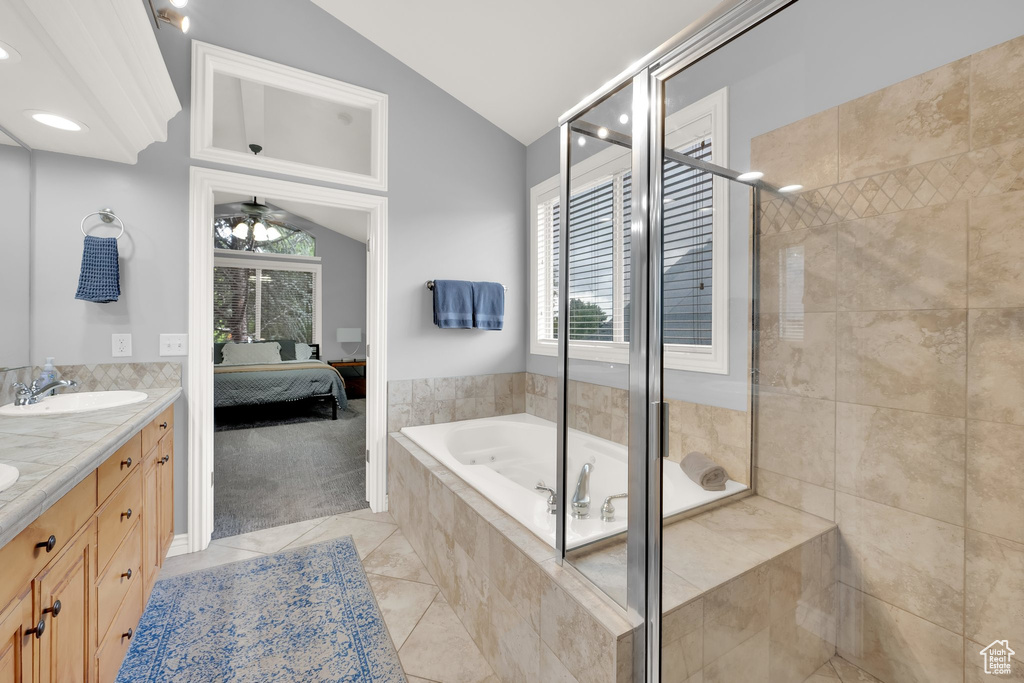 Ensuite bathroom with lofted ceiling, double vanity, a bath, a shower stall, and tile patterned flooring