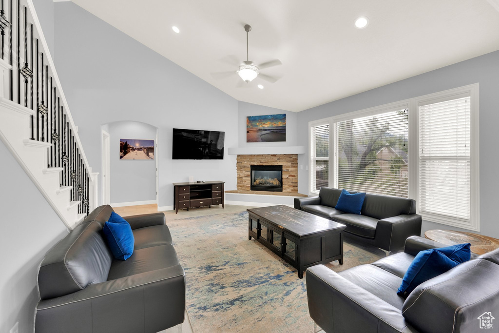 Living room featuring a ceiling fan, baseboards, a stone fireplace, recessed lighting, and high vaulted ceiling