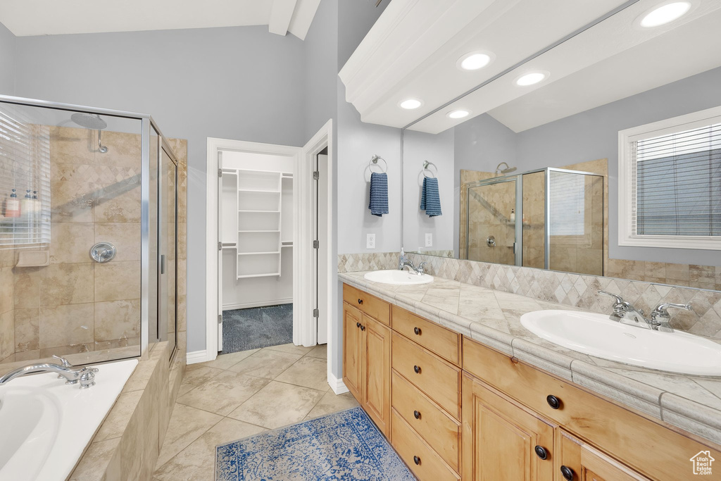Bathroom featuring a shower stall, vaulted ceiling, a walk in closet, double vanity, and a garden tub