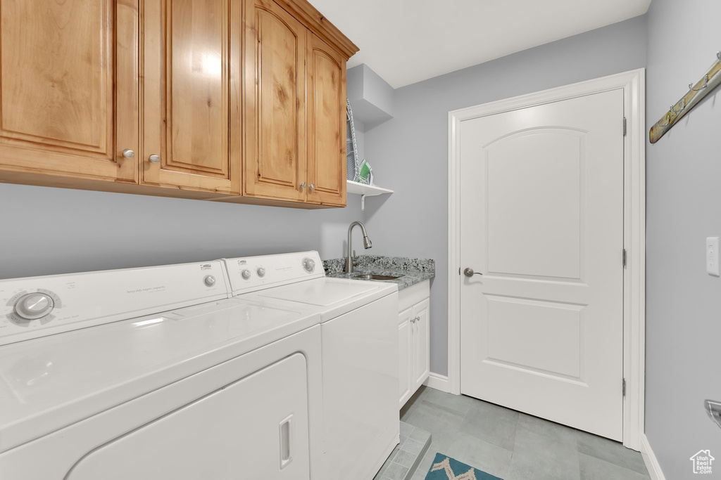 Clothes washing area with washer and dryer, baseboards, and cabinet space
