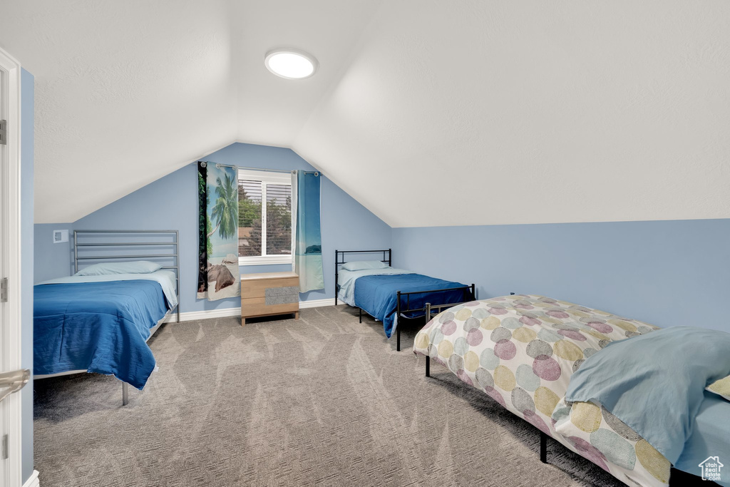 Bedroom featuring carpet, lofted ceiling, and baseboards