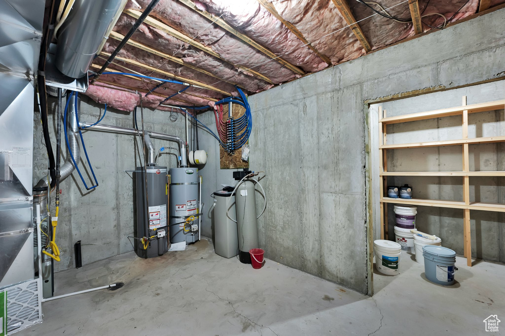 Unfinished below grade area with water heater, a water softener, strapped water heater, and heating unit