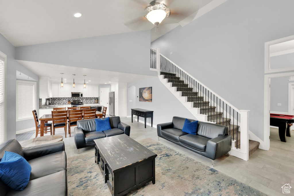 Living area featuring stairs, a ceiling fan, high vaulted ceiling, recessed lighting, and baseboards