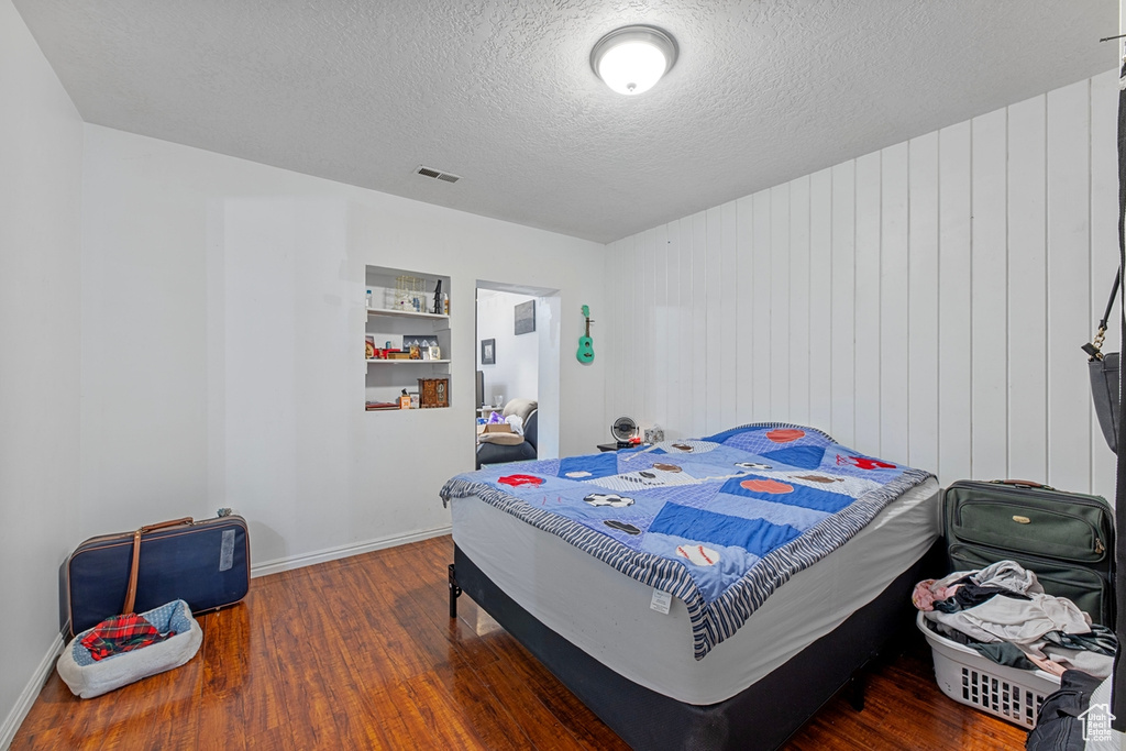 Bedroom featuring wood finished floors, a textured ceiling, and baseboards