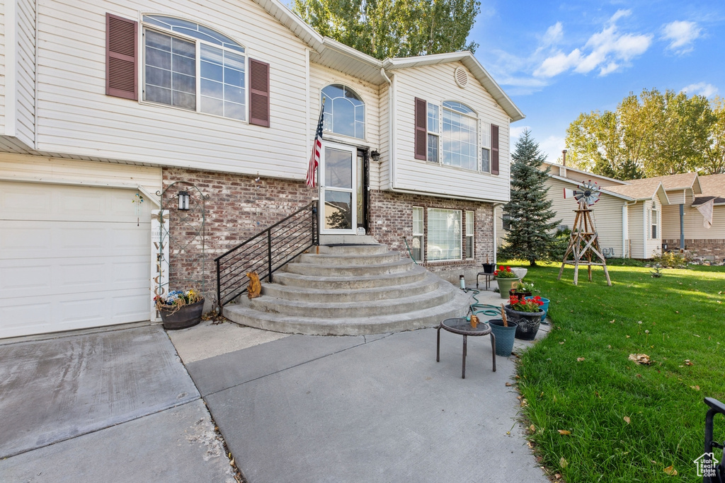 View of front of property featuring brick siding, a front yard, an attached garage, and concrete driveway