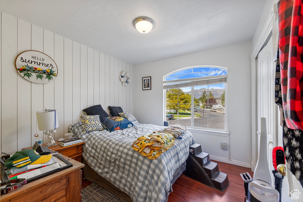 Bedroom featuring wood finished floors, baseboards, and wood walls