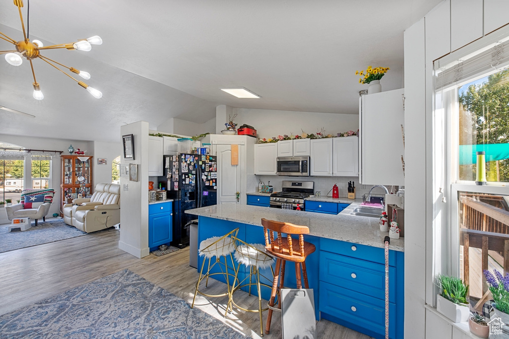 Kitchen featuring stainless steel appliances, a sink, vaulted ceiling, open floor plan, and a peninsula
