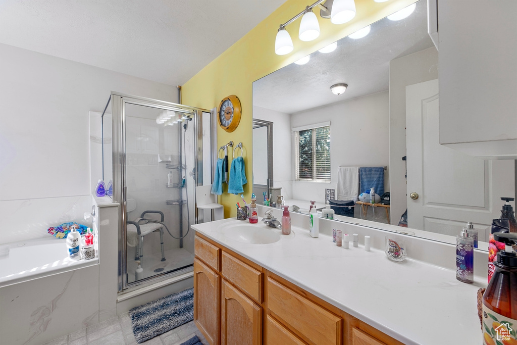 Full bathroom featuring vanity, a stall shower, a garden tub, and tile patterned flooring
