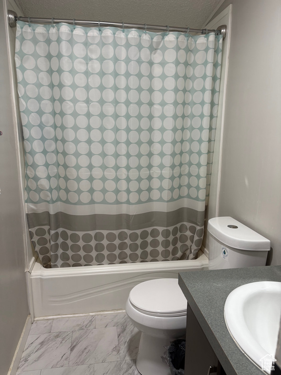 Bathroom featuring toilet, shower / tub combo, vanity, marble look tiles, and baseboards